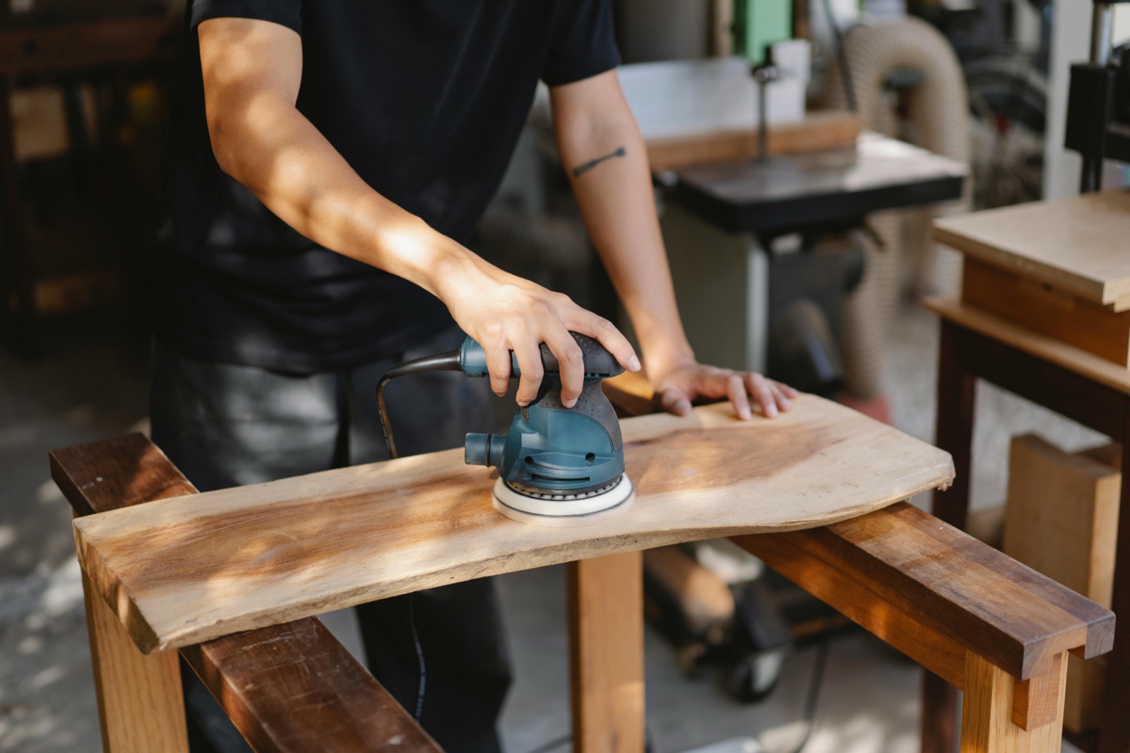 A woodworker sanding a live-edge wooden board in a workshop
